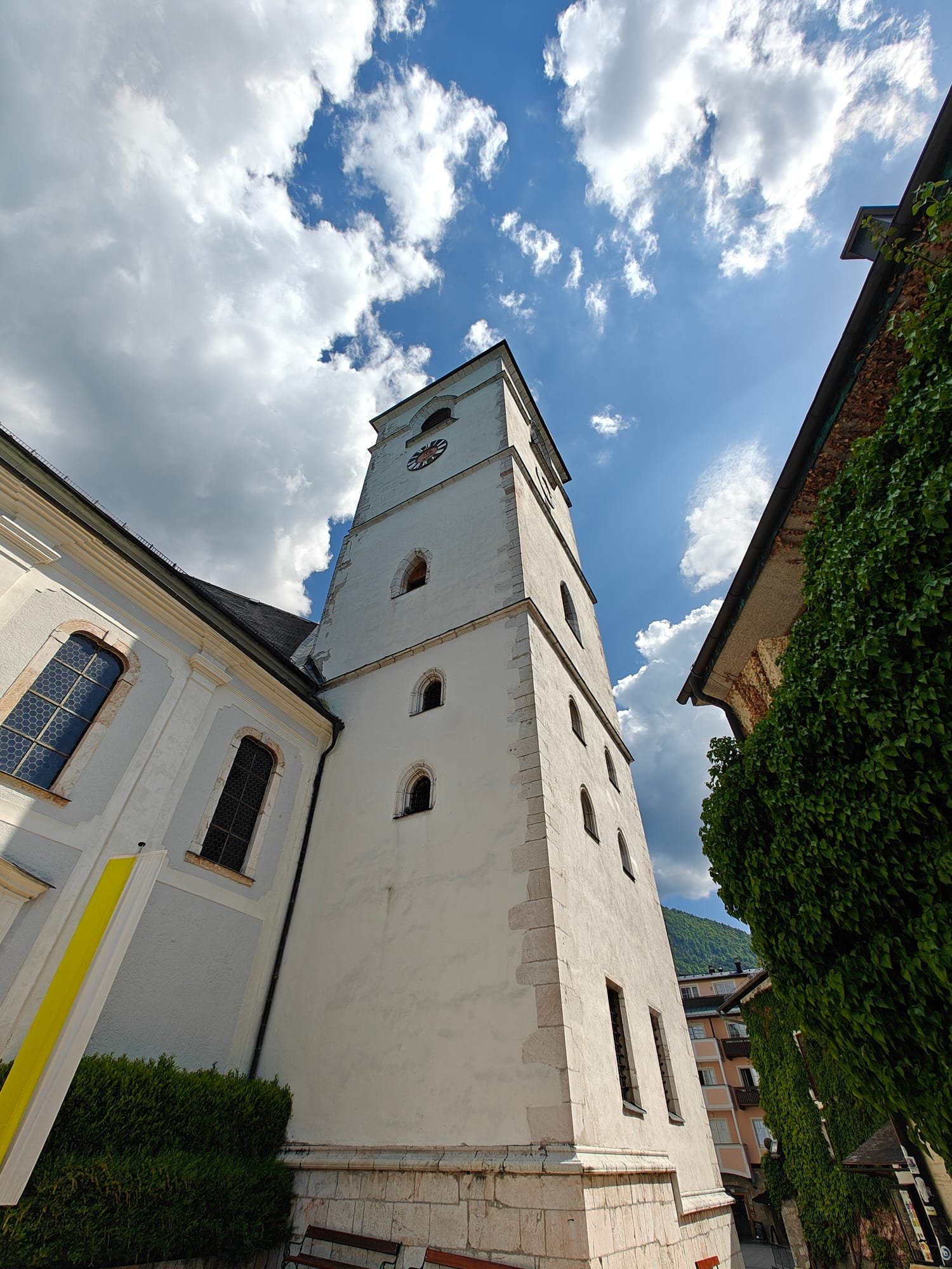 Weisser Kirchturm vor blauem Wolkenhimmel